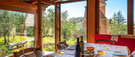A dining area with a table set for two, a bottle of olive oil, and a bowl of olives.