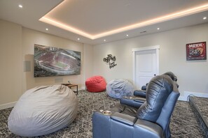 A home theater room with a large flat-screen TV, a bean bag, and leather recliners.
