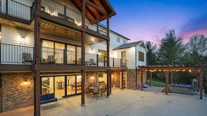 A multi-story residential building with a covered patio area, outdoor seating, and a barbecue grill. - Heavenly View | Hocking Hills, Pool, Theater (Logan)
