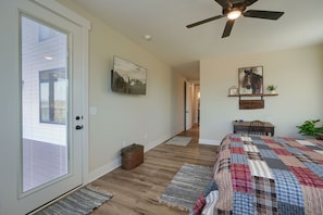 A bedroom with a bed, a ceiling fan, a mounted TV, and a door leading to another room. - Heavenly View | Hocking Hills, Pool, Theater (Logan)