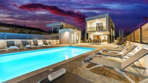 A modern outdoor pool area with lounge chairs and a two-story building in the background. - Stunning home in Zaton with private swimming pool, can be inside or outside (Zaton)