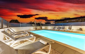 Une piscine avec des chaises longues et une vue sur le coucher de soleil.