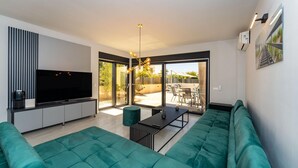 A modern living room with a flat-screen TV, teal sofas, and a dining area with a table and chairs. - Stunning home in Zaton with private swimming pool, can be inside or outside (Zaton)