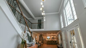 A spacious interior with a wooden staircase, a kitchen area, and a dining space. - Spacious Lake House with Dock and Swimming Pool (Dawsonville)