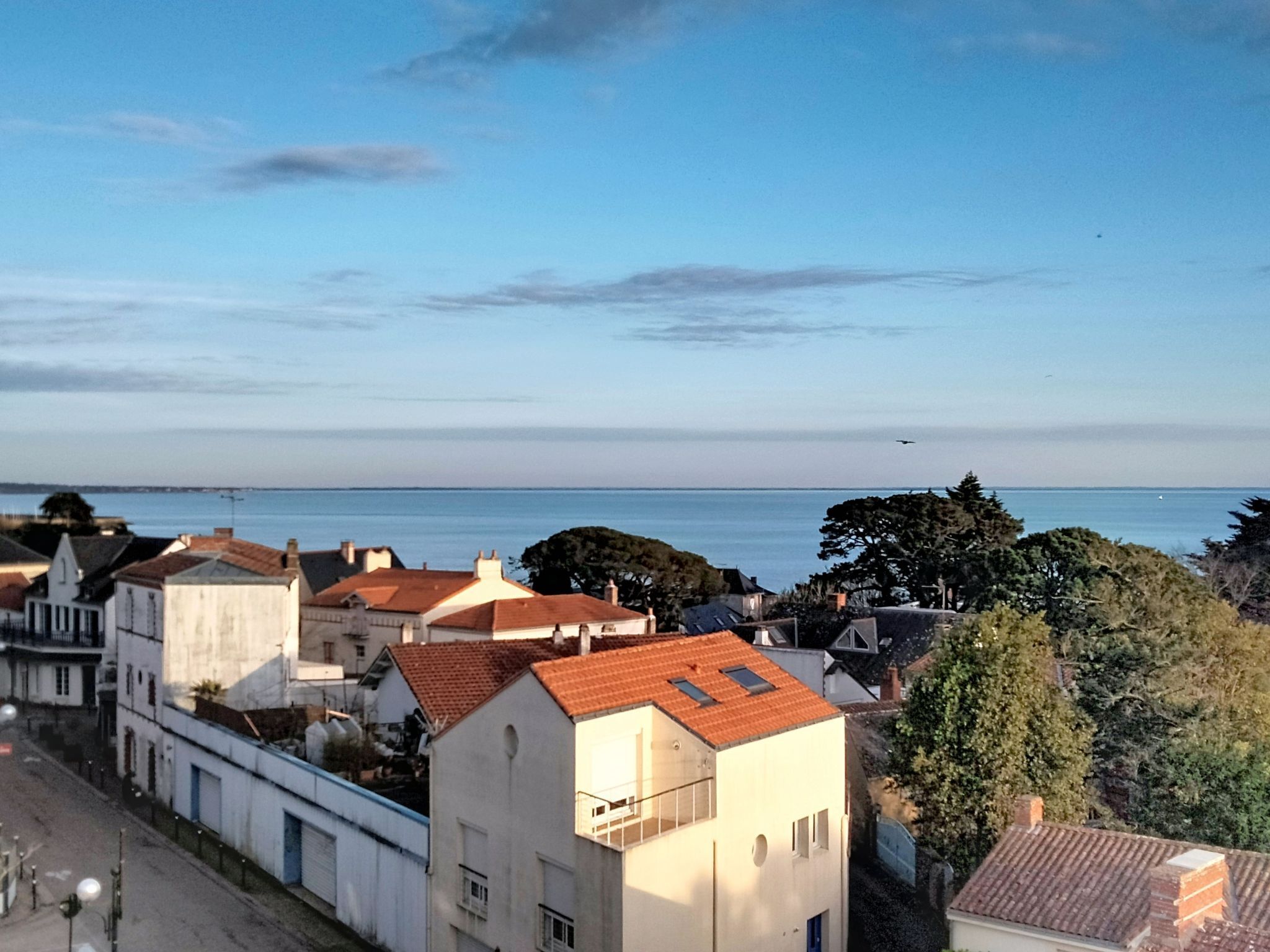 Et kystnært boligområde med bygninger, klar himmel og udsigt til havet.