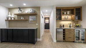 A modern kitchen with dark cabinetry, wooden shelves, and a central island. - Stunning Canal Front Home Exquisite Design! (Sanibel)