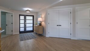 A spacious hallway with wooden flooring, a dining area with a table and chairs, and a large wardrobe with two doors. - Stunning Canal Front Home Exquisite Design! (Sanibel)