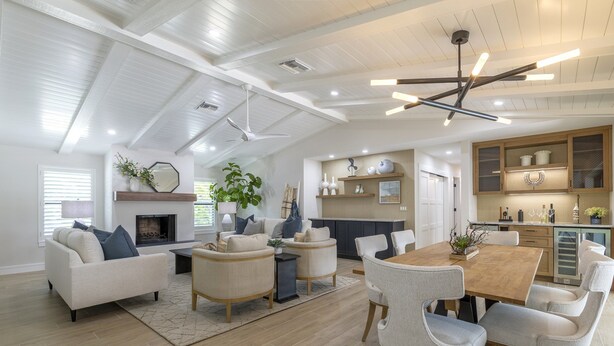 A spacious living area with a high ceiling, a fireplace, and a dining table with chairs. - Stunning Canal Front Home Exquisite Design! (Sanibel)