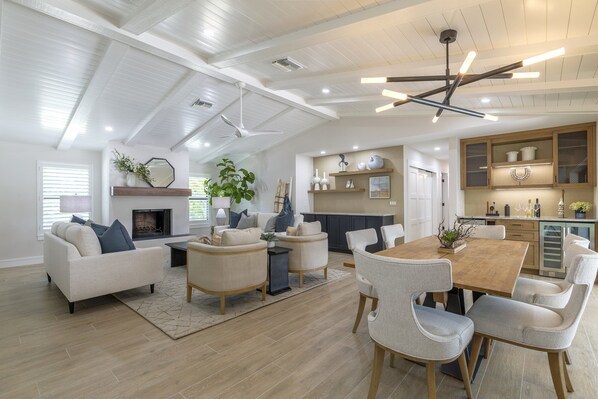 Enjoy a spacious open-plan living space with a high ceiling and exposed beams, featuring a comfortable seating area, dining table, and kitchen.