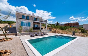 A modern two-story house with a swimming pool, outdoor seating, and a stone facade. - Nice home in Rovanjska (Rovanjska)