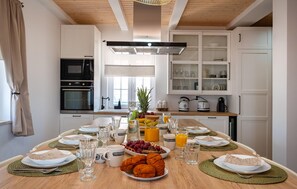 A modern kitchen with white cabinets, a central island with breakfast items, and a window providing natural light. - Nice home in Rovanjska (Rovanjska)
