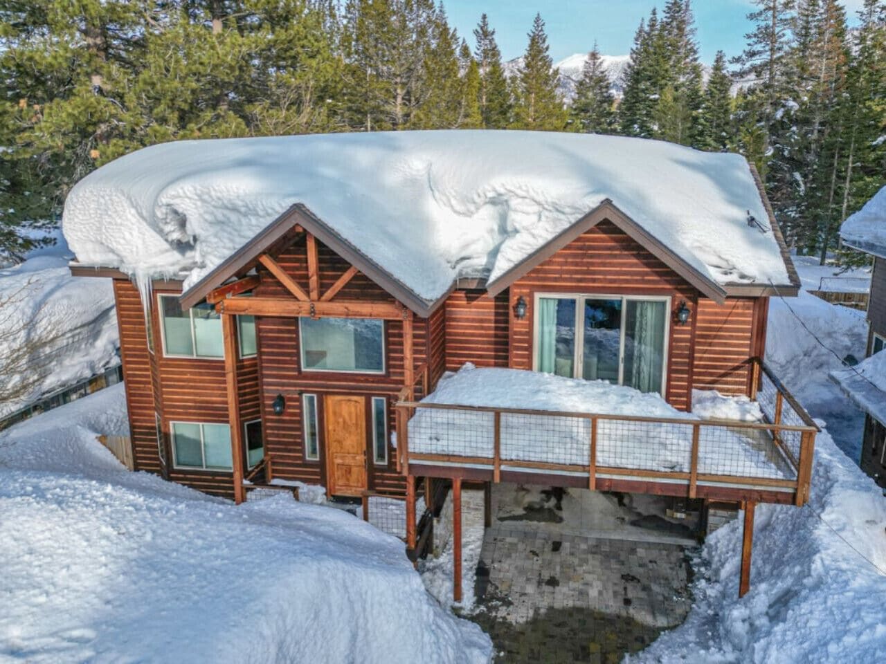Eine Holzhütte mit verschneitem Dach, einer Haustür und einem Balkon.