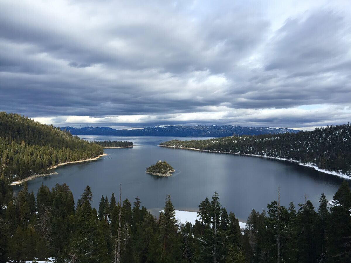 Vista panorámica de un lago rodeado de bosques densos y montañas.