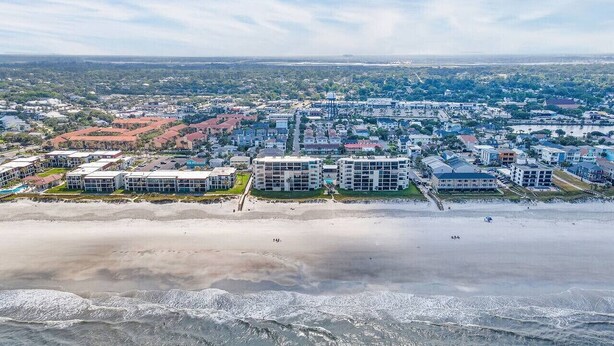 A coastal cityscape with beachfront hotels, a sandy beach, and ocean waves.