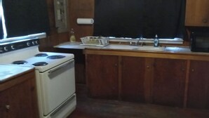 A compact kitchen with a white stove, wooden cabinets, a microwave, and a small sink.