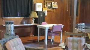 A room with wooden flooring, a wooden desk, a chair, a cushioned bench, and a small table.