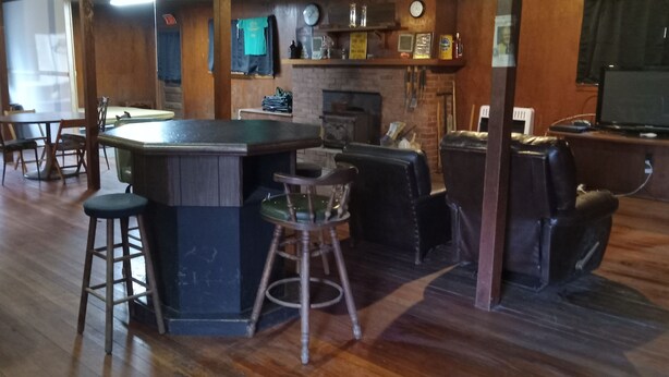 A bar area with stools, a counter, and a fireplace.