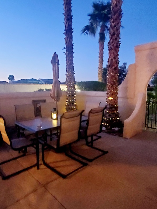 An outdoor patio with a table and chairs, palm trees, and a view of the landscape. - The Island Barcelona @ the Nautical Estates. Boat parking,
2 car garage, pool. (Lake Havasu City)
