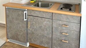 Eine Küche mit grauen Schränken, Holz Arbeitsplatten, einer Spüle und einem Herd.
