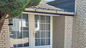 Ein Haus mit weißer Tür, einer kleinen Veranda und einer Ziegelaußenwand.