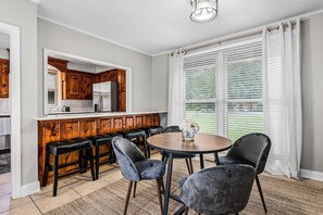 Eine Küche mit Holzausstattung, einem Kühlschrank und einem Essbereich mit rundem Tisch und Stühlen.