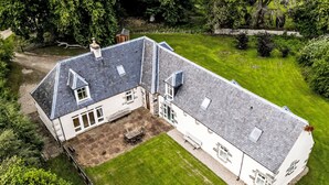 A large, two-story house with a sloped roof, a fenced backyard, and a well-maintained lawn. - Old Stables by Interhome (Drumnadrochit)