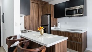Une cuisine moderne dotée d’un îlot central, de meubles en bois, d’un réfrigérateur en acier inoxydable et d’un four à micro-ondes encastré.