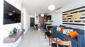Un salon moderne avec un téléviseur, un canapé et un coin repas.