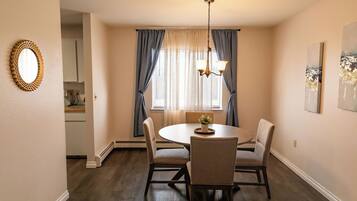 Enjoy meals in this cozy dining area with a round table and four chairs, featuring a central light fixture and a beautiful painting on the wall.