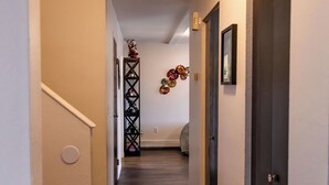 A hallway with a wooden floor, white walls, and a black door on the right. - Family-size condo in the heart of Fairbanks! Short walk to Creamer's field.  (Fairbanks)
