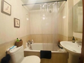 Bathroom features a bathtub, toilet, and sink with a mirror.