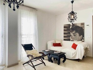 A living room with a white sofa, a chair, a coffee table, and a chandelier.