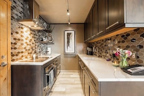A modern kitchen with a central island, stainless steel appliances, and a honeycomb-patterned backsplash.