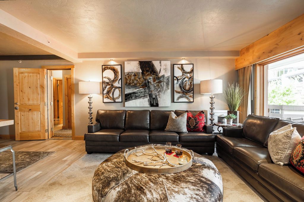 A modern living room with a leather sofa, a round coffee table, and abstract wall art.