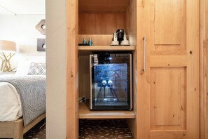 A compact room with a bed, a small wooden cabinet, and a refrigerator. - Upscale Traditional Condo steps from Vail MTN w/ fireplace, hot tub + spa access (Vail)