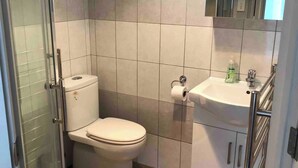 Un baño con inodoro, lavamanos y cabina de ducha.