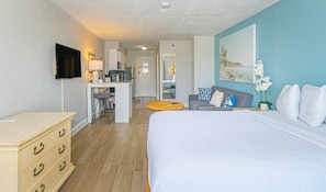 A hotel room with a bed, a desk, a chair, a sofa, and a TV.