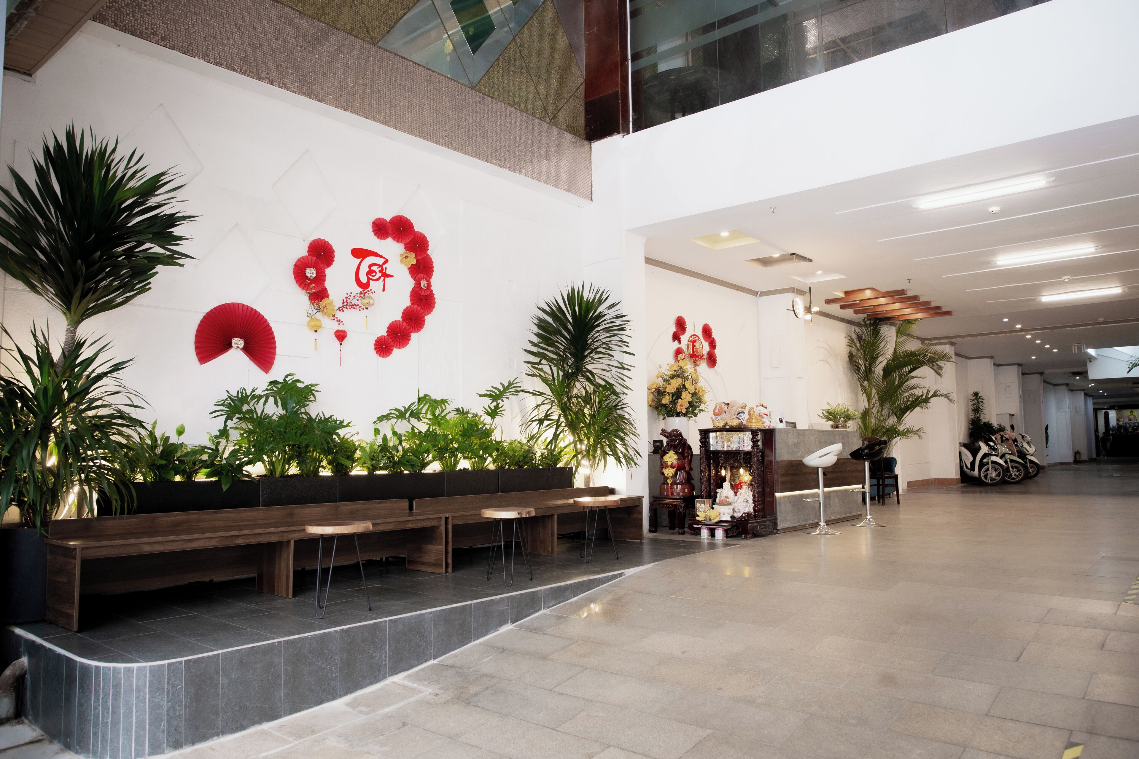 A spacious lobby with a reception desk, seating area, and decorative plants.
