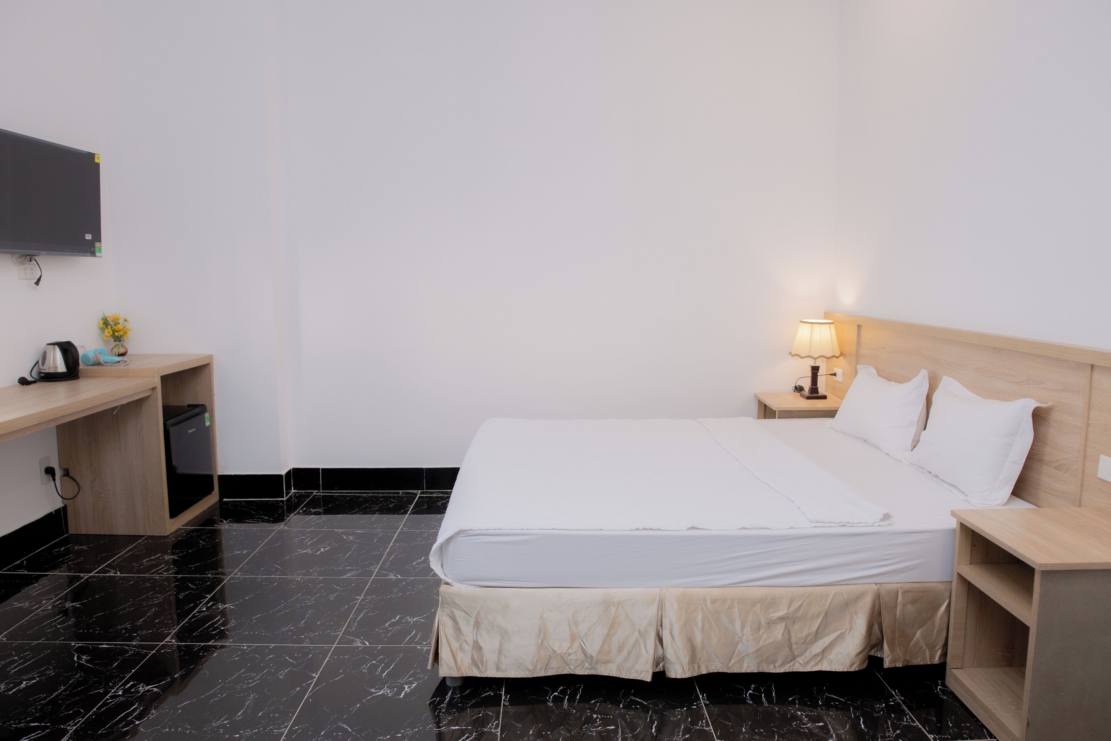 Une chambre d’hôtel équipée d’un lit, d’un bureau, d’une télévision et d’une table de chevet avec une lampe.