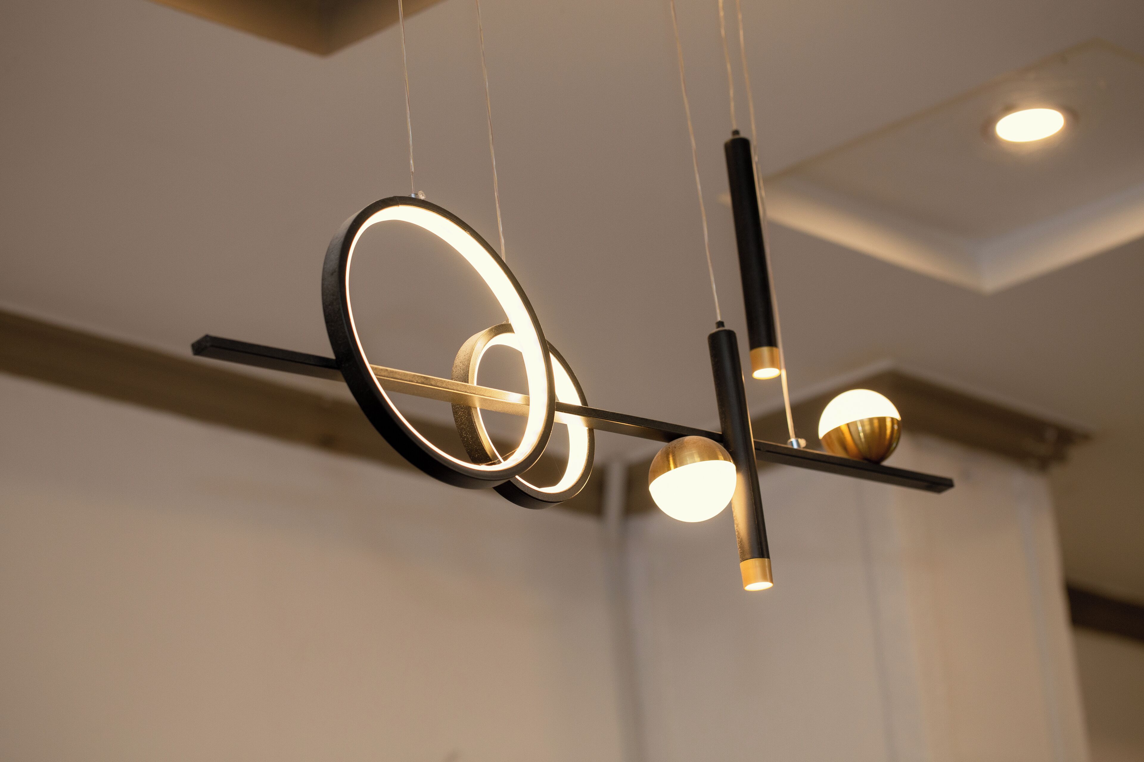 Ein moderner Kronleuchter mit mehreren Leuchten, darunter runde und kugelförmige Designs, an einer schwarzen Metallkonstruktion befestigt.
