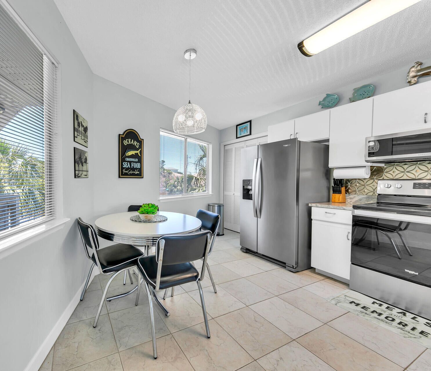 A modern kitchen with white cabinets, stainless steel appliances, and a dining area with a round table and chairs.