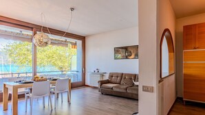 A modern living room with a dining area, large windows, and a view of the outdoors. - Attilio lake front view by Interhome (Ispra)