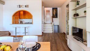 A modern kitchen with wooden cabinets, a bar area, and a dining table set with glasses and fruits. - Attilio lake front view by Interhome (Ispra)