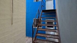 A narrow stairway leading to a blue building with a window and a door. - ALOJAMENTO POUSADA (Campinas)