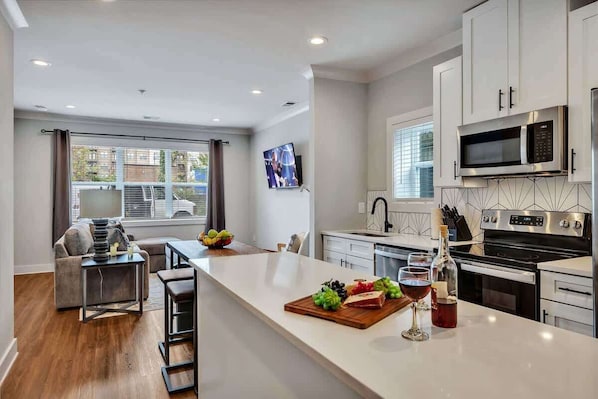 A modern kitchen with white cabinets, a central island, and a dining area with a sofa and chairs.
