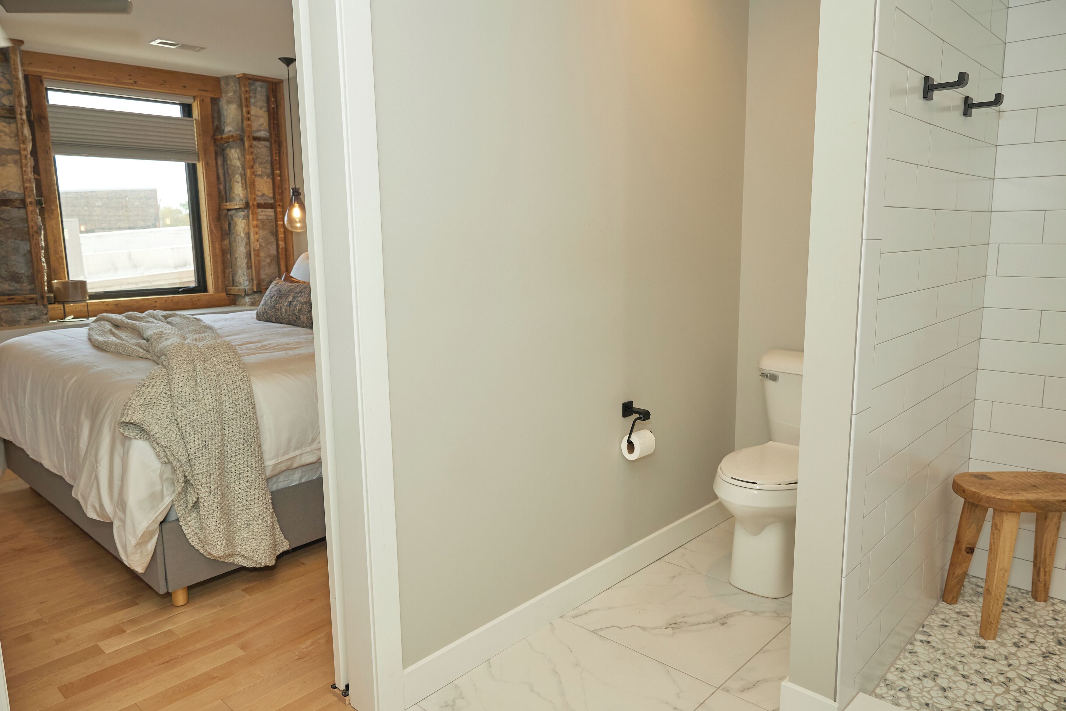 Une chambre à coucher avec un lit, une fenêtre et une salle de bain comprenant des toilettes et une douche.