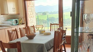 Un coin repas avec une table dressée pour six personnes, des chaises en bois, un bol et un verre posés sur une étagère en verre.