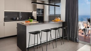 Una cocina moderna con una isla central, taburetes de bar y vistas de la ciudad.
