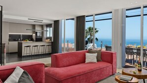Una sala moderna con un sofá rojo, una pequeña mesa de madera y vista al océano.