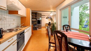 A modern kitchen with a dining area, wooden ceiling, and a view of the outdoors. - Apartment 'Stumpp´s Appartement' with Private Terrace, Wi-Fi and Air Conditioning (Heroldstatt)